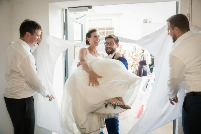 Bräutigam trägt Braut durch das zerschnittene Bettlaken im das Loft-Spandau macht Hochzeitsbilder während der Hochzeitsfeier