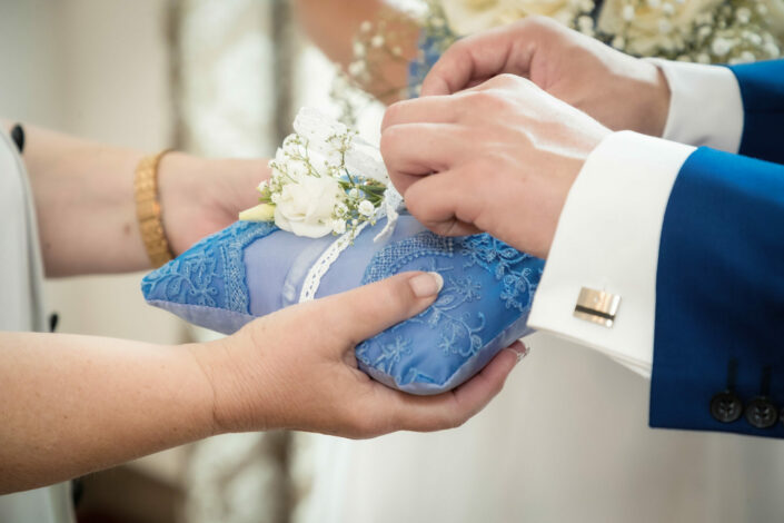 Bräutigam nimmt Ring vom Ringkissen während der Trauung
