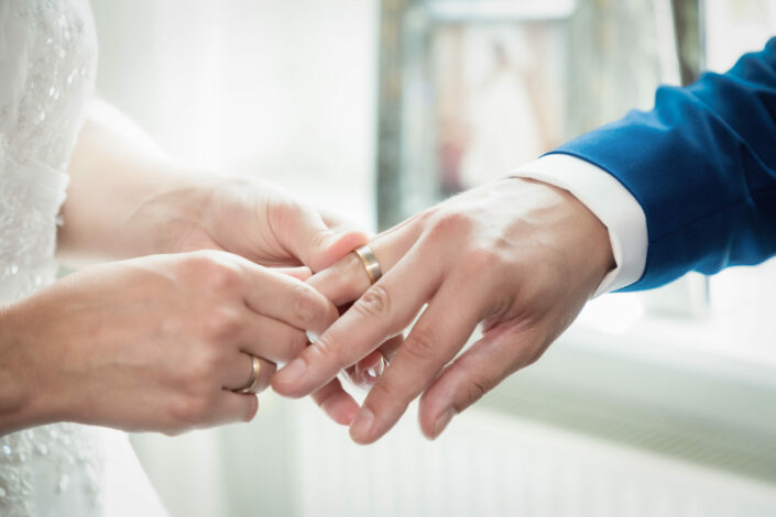 Braut steckt Bräutigam den Ring an im Standesamt Falkensee macht Hochzeitsbilder während des Ringwechsels