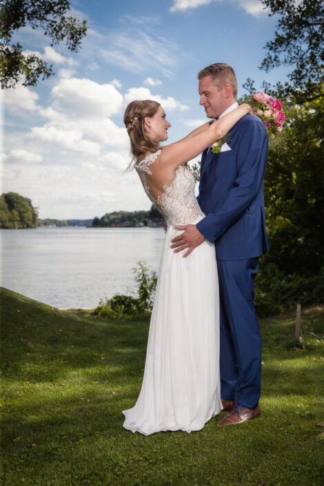 Hochzeitsfotograf Berlin macht professionelle Hochzeitsbilder: Braut umarmt den Bräutigam, im Hintergrund. der Lehnitzsee