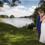 Kreative Hochzeitsbilder vom Hochzeitsfotograf Berlin: Braut umarmt von hinten den Bräutigam, im Hintergrund. der Lehnitzsee