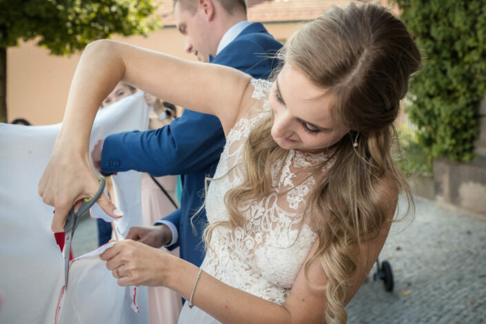 Bild vom Hochzeitsfotograf Berlin aus der Hochzeitsreportage: Braut zerschneidet Hochzeitsherz im Bettlaken vor dem Standesamt Potsdam