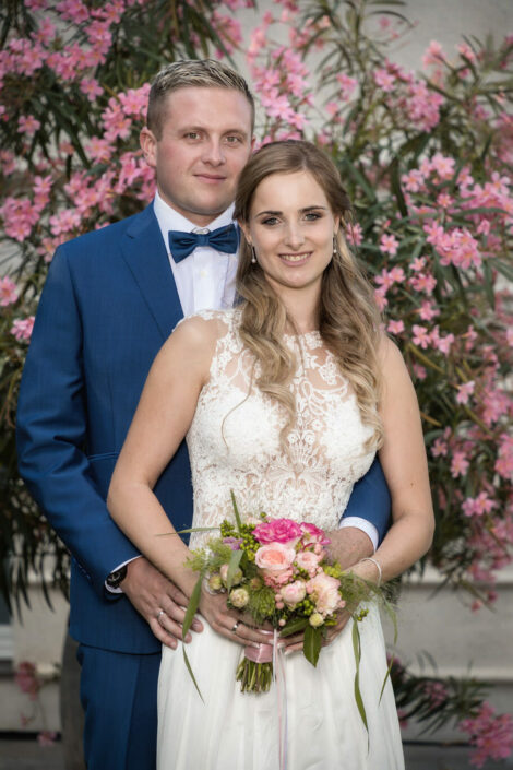 Hochzeitsfotograf bei Brautpaarshooting: Brautpaar umarmt sich vor einem Oleander-Baum