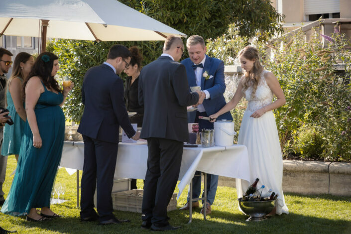 Hochzeitsfotograf Potsdam macht authentische Hochzeitsbilder – auf dem Hochzeitsfoto wird abgebildet: Brautpaar serviert seinen Gästen Hochzeitstorte bei der Hochzeitsfeier im Landhaus Adlon Potsdam am Lehnitzsee